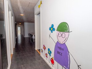 A hallway with a white wall featuring a cartoon character holding a flower and a sign saying '100% NICE'.