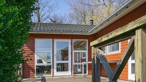 A wooden deck leading to a red building with large windows and a white door. - 4 Star Holiday Home in Allinge (Allinge)