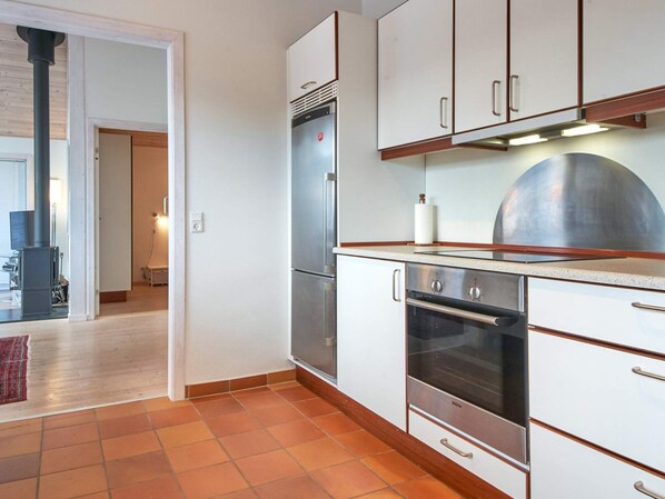 A kitchen with white cabinets, a Bosch oven, and a stainless steel refrigerator.