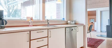 A modern kitchen with a dishwasher, a coffee maker, and a toaster on the counter.