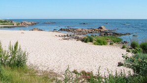 A sandy beach with rocky outcrops and greenery in the foreground. - 4 Star Holiday Home in Allinge (Allinge)