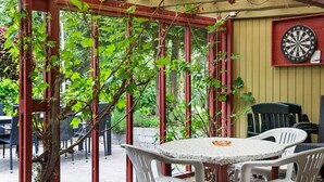 Eine Außenpatio mit Tisch und Stühlen, einem Dartspiel und einer Pergola mit Kletterpflanzen.