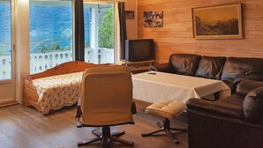 Un saló agradable amb interior de fusta, un sofà, una cadira, una taula petita i una televisió.