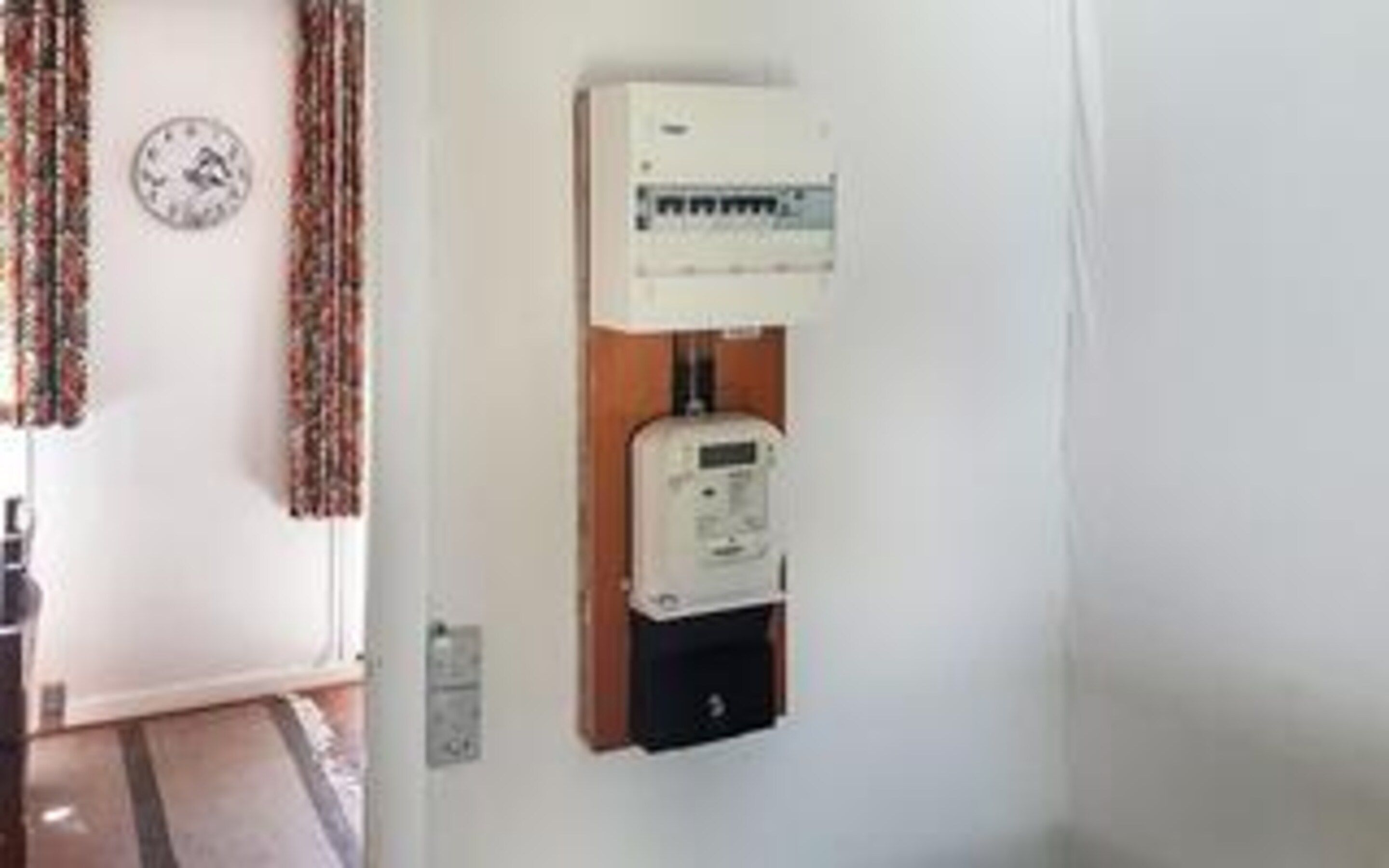 A wall-mounted electrical panel with a clock and a power outlet.