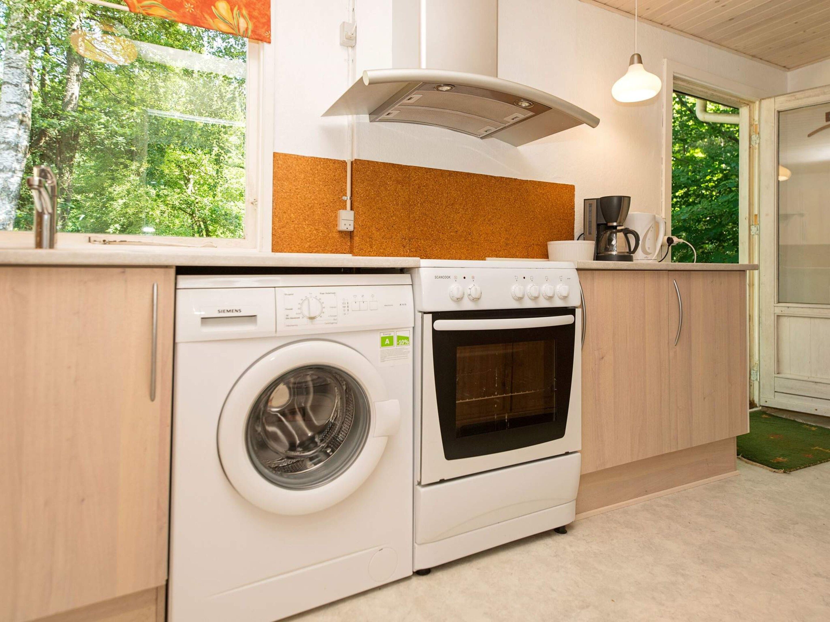 Cocina funcional con lavadora, horno y cafetera sobre la encimera.
