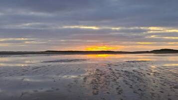 A flat landscape with a sunset over a body of water.