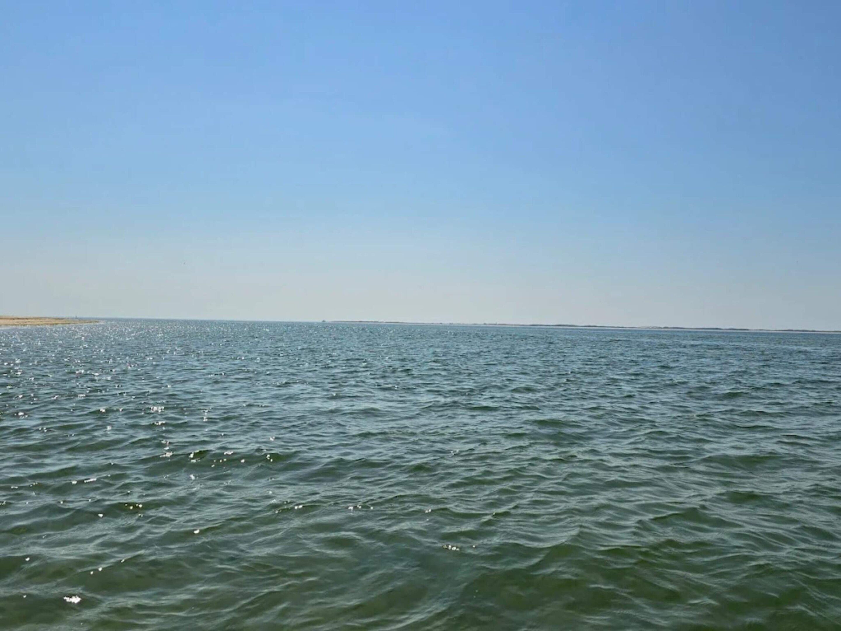 A calm sea with gentle waves and a clear sky.