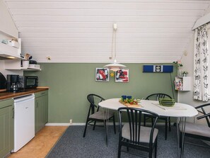 A compact kitchen with a dining area, featuring a white refrigerator, a microwave, and a coffee maker on the counter. There are two chairs around a small table, and a ceiling fan above. - 4 Person Holiday Home in Romo-by Traum (Rømø)
