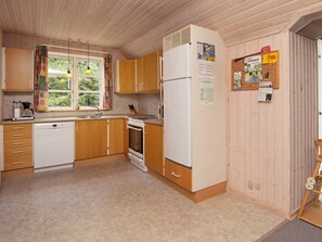 A compact kitchen with wooden cabinets, a white refrigerator, a stove, and a sink. - Comfortable Holiday Home in Rømø With Sauna (Rømø)