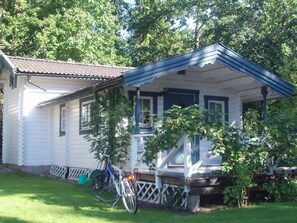 A white house with a blue roof and a porch. There is a bicycle parked in front of the house. - 3 Person Holiday Home in Vastervik (Vastervik)
