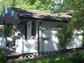 A small, single-story house with a porch, a chimney, and a utility box. - 3 Person Holiday Home in Vastervik (Vastervik)