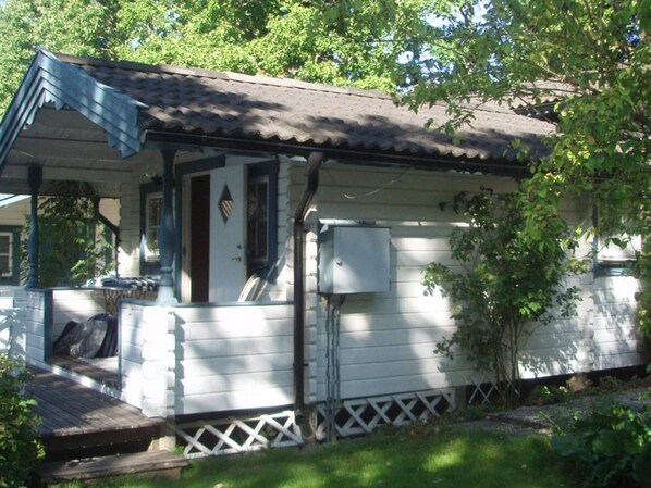 A single-story house with a porch, a small window, and a utility box.