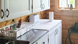 A kitchen with white cabinets, a stainless steel sink, and a window with a view of greenery. - 3 Person Holiday Home in Vastervik (Vastervik)