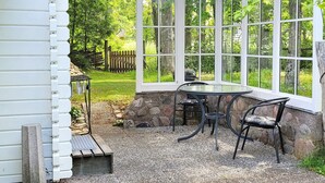 A covered patio with a stone wall, a table, and two chairs. - 3 Person Holiday Home in Vastervik (Vastervik)