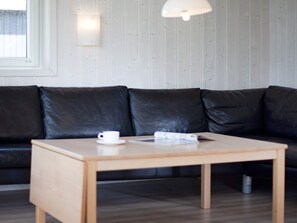 A modern living room with a black leather sofa, a wooden coffee table, and a white cup.