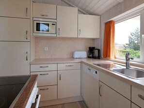 A compact kitchen with a microwave, toaster, and coffee maker on the countertop, a sink with a faucet, and cabinets with handles.