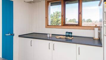 A kitchen with white cabinets, a black countertop, a window with a view, and a blue door.