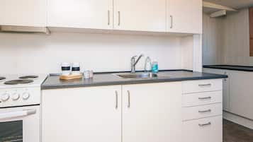 Una cocina con gabinetes blancos, un lavamanos de acero inoxidable y una estufa.