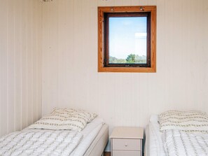 Une chambre avec deux lits, une table de chevet et une fenêtre donnant sur des arbres.