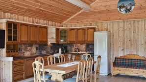 Un interior de madera con una mesa de comedor, sillas, un refrigerador y un banco.