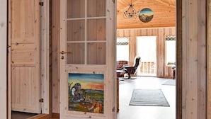 Un interior de madera con una puerta grande que muestra una pintura de un paisaje.
