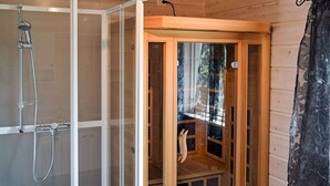 Una cabaña de madera con cerramiento de ducha de vidrio y un mueble de madera.