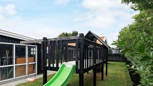 Une aire de jeux avec un toboggan vert et une structure de jeu en bois.