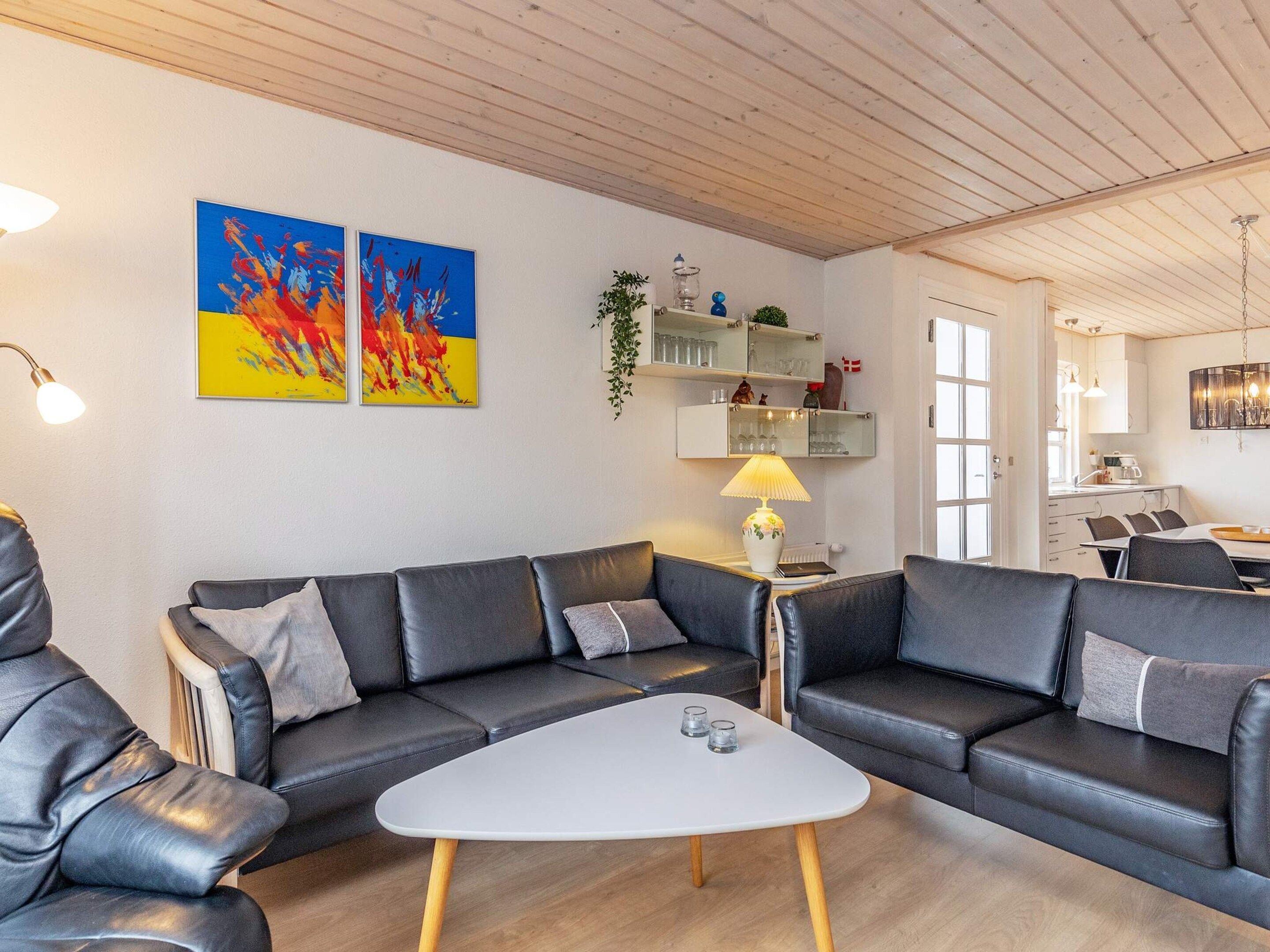 Un salon moderne comprenant un ensemble de canapés, une table basse et un coin repas avec des chaises et une table.