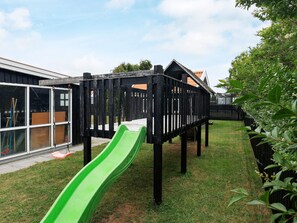 Une aire de jeux avec un toboggan vert et une structure de jeu en bois.