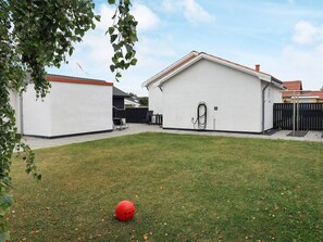 Ein Wohngebiet mit Rasen, einem roten Ball und einem weißen Gebäude mit rotem Dach.