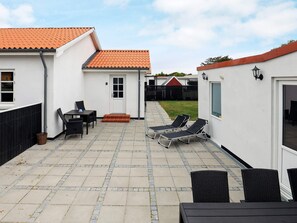 A patio area with a table and chairs, a small step leading to a door, and a fenced backyard.
