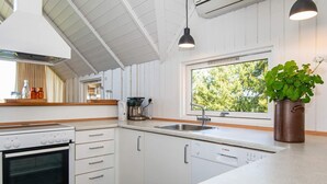 Una cucina moderna con mobili bianchi, una lavastoviglie Bosch, una macchina per caffè e una finestra vista alberi.