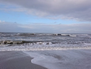 Una playa con olas y un cielo nublado.