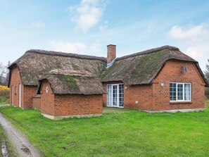 A traditional brick house with thatched roofs and a chimney.