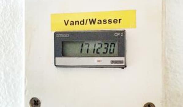 A digital water meter with a yellow label reading 'Vand/Wasser' and the number '171230' displayed.