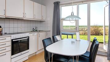 Una cocina moderna con zona de comedor, ventanas grandes y vistas al campo.