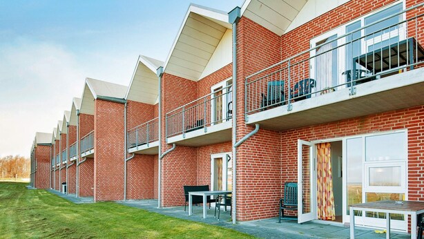 A row of brick buildings with balconies, outdoor seating, and a grassy area. - 4 Star Holiday Home in Hojer (Højer)