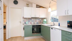 A modern kitchen with green cabinets, a tiled backsplash, a built-in oven, and a dishwasher.