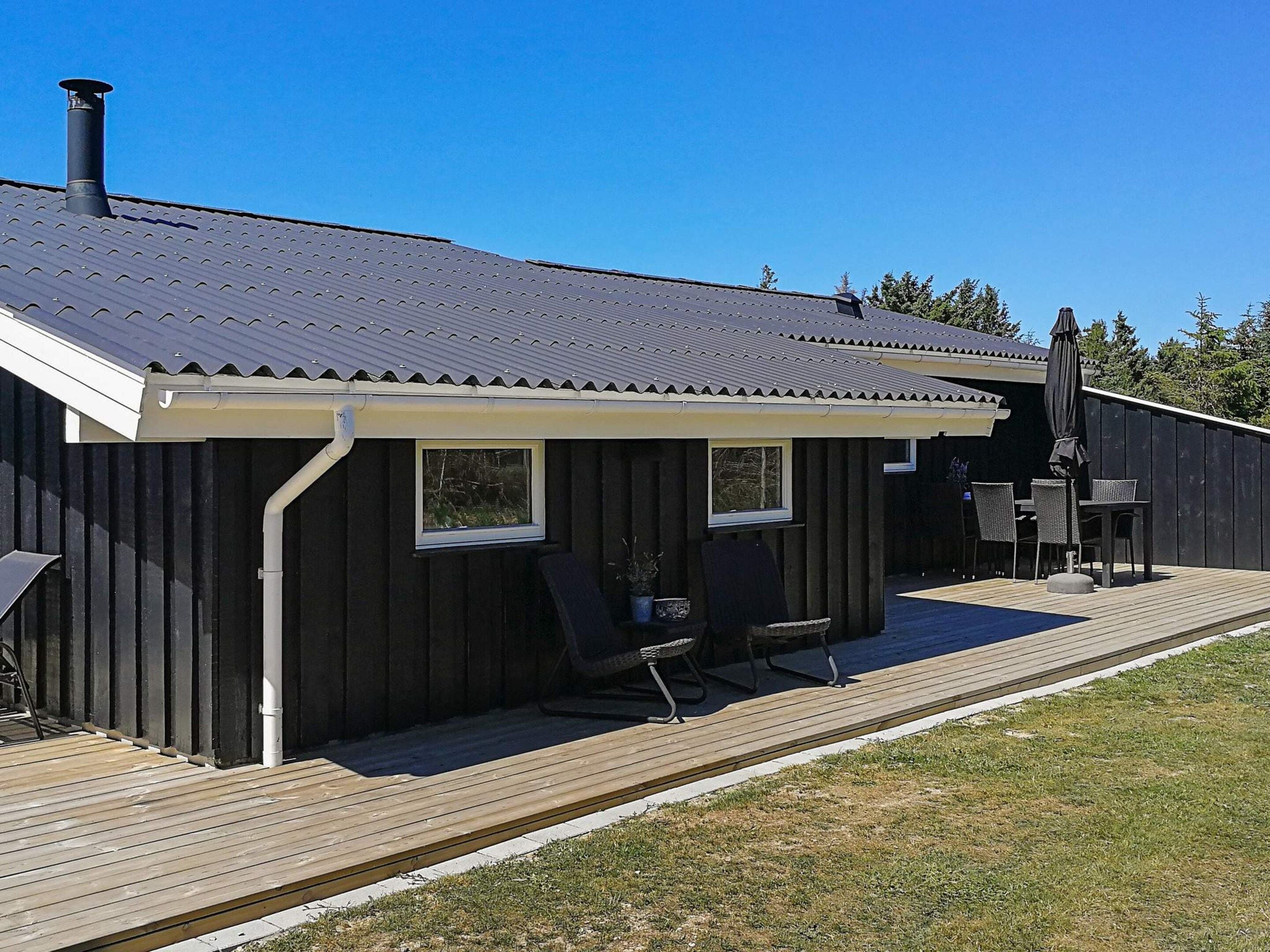 A wooden deck with a covered patio area, a chimney, and outdoor furniture.