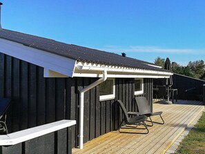 Um deck de madeira com uma cadeira de metal preta e um corrimão branco.
