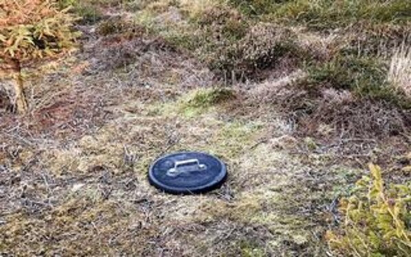 A circular object with a keyhole on a grassy surface.