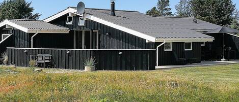 A modern two-story building with a sloped roof, a satellite dish, and a fenced outdoor area with a bench.