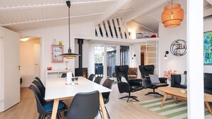 A modern dining area with a white table, black chairs, and a hanging light fixture.