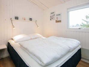 Quarto com cama, janela e decorações nas paredes.