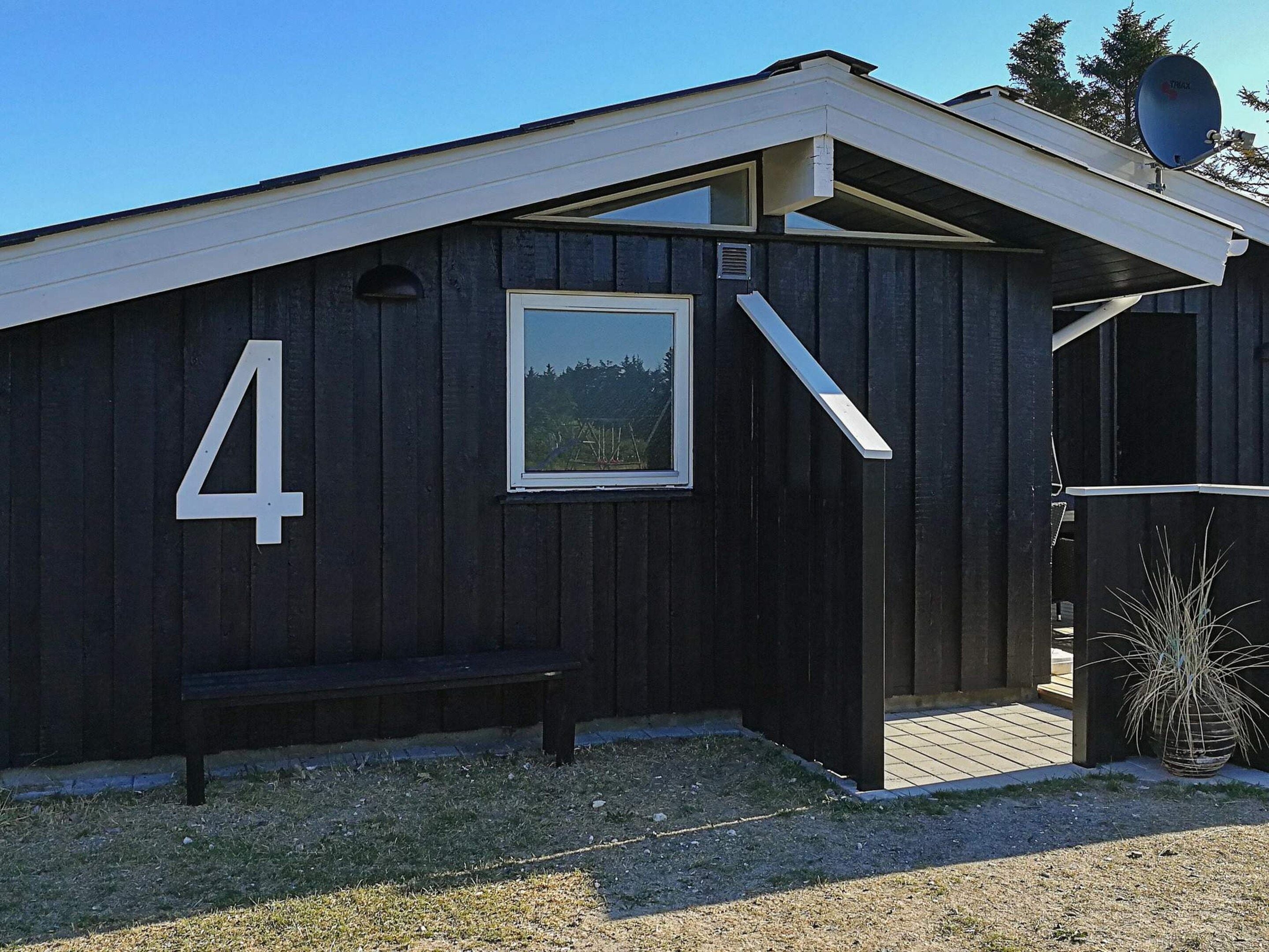 Un bâtiment en bois portant le numéro 4, un banc et une antenne parabolique.