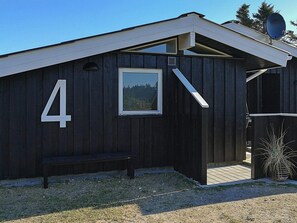 Ein Holzhaus mit der Nummer 4, einer Bank und einer Satellitenschüssel.