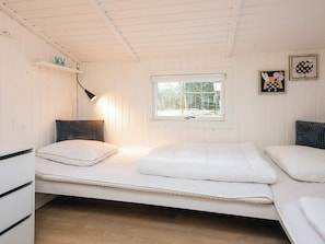 Ein Einzelzimmer mit Fenster, Nachttischlampe und einer kleinen Ablage mit Dekoration.