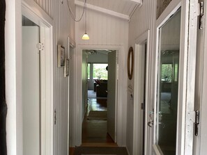 A hallway with white paneled walls, a hanging light fixture, and a door with a glass panel. - 6 Person Holiday Home in Norre Nebel (Norre Nebel)