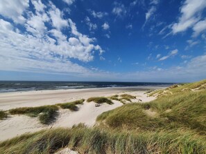 Une plage avec des dunes de sable et un ciel dégagé.