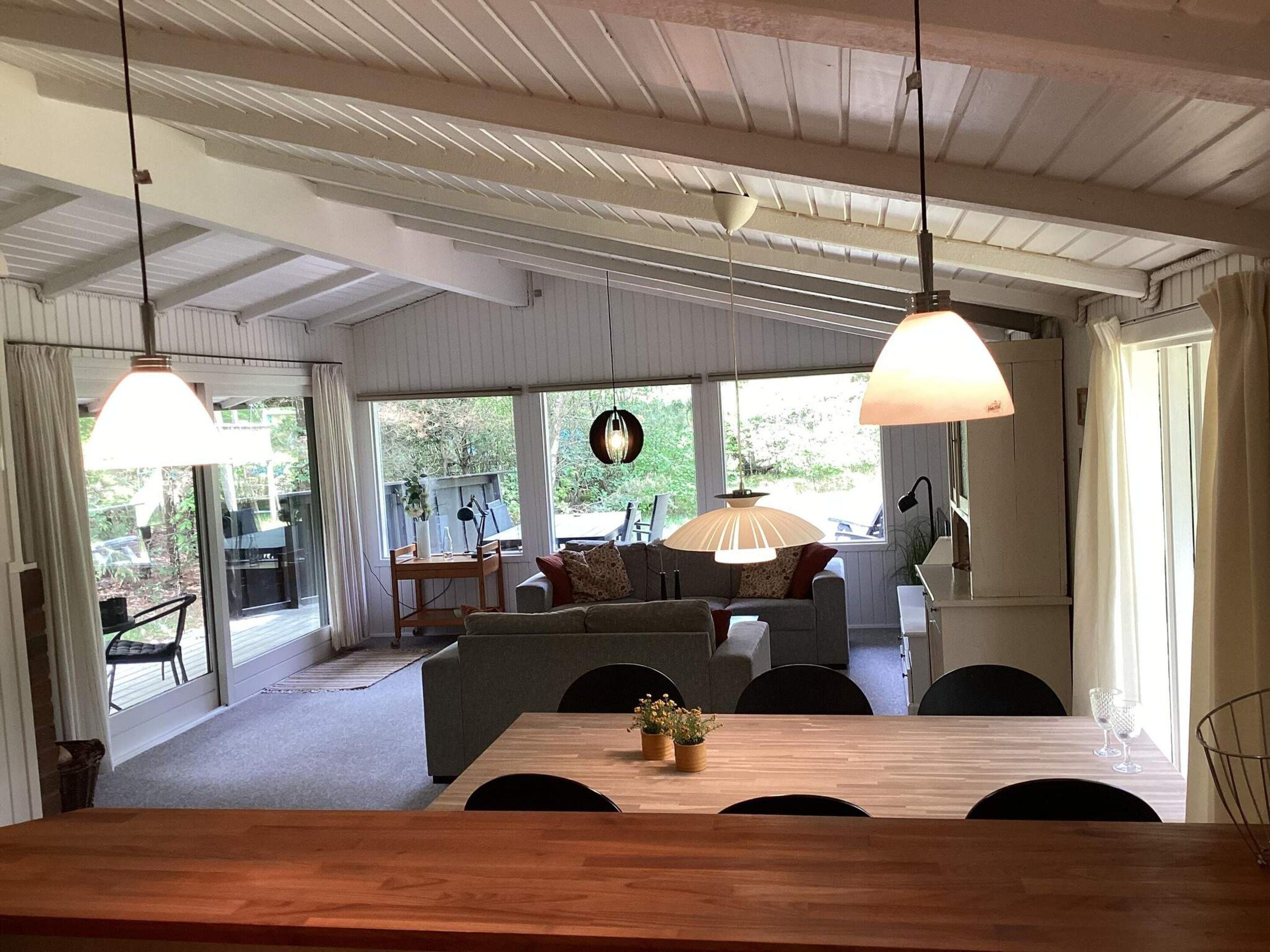 Un espace repas avec une table en bois, des chaises et un canapé à l’arrière-plan.